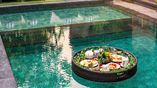 Una piscina con sillas de descanso y un área de comedor flotante.