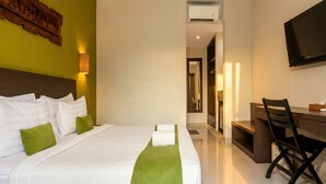 Habitación de hotel con una cama grande, un escritorio, una silla, un televisor de pantalla plana y un equipo de aire acondicionado.
