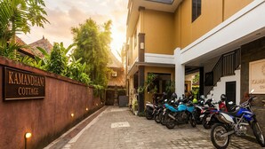 Una entrada cerrada a Kamandhani Cottage, con un camino de entrada pavimentado y motocicletas estacionadas.