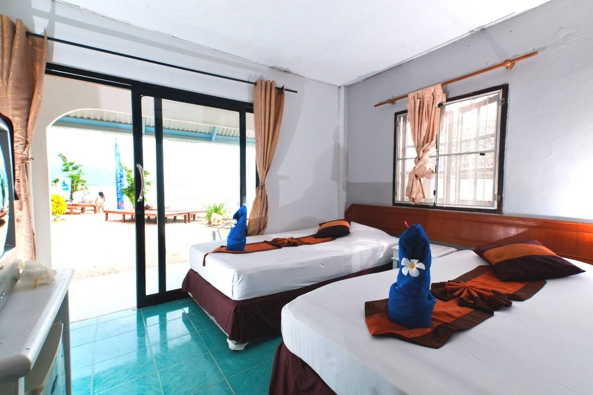 Ein Hotelzimmer mit zwei Betten und Blick auf den Strand, inklusive einer Schiebeglastür.