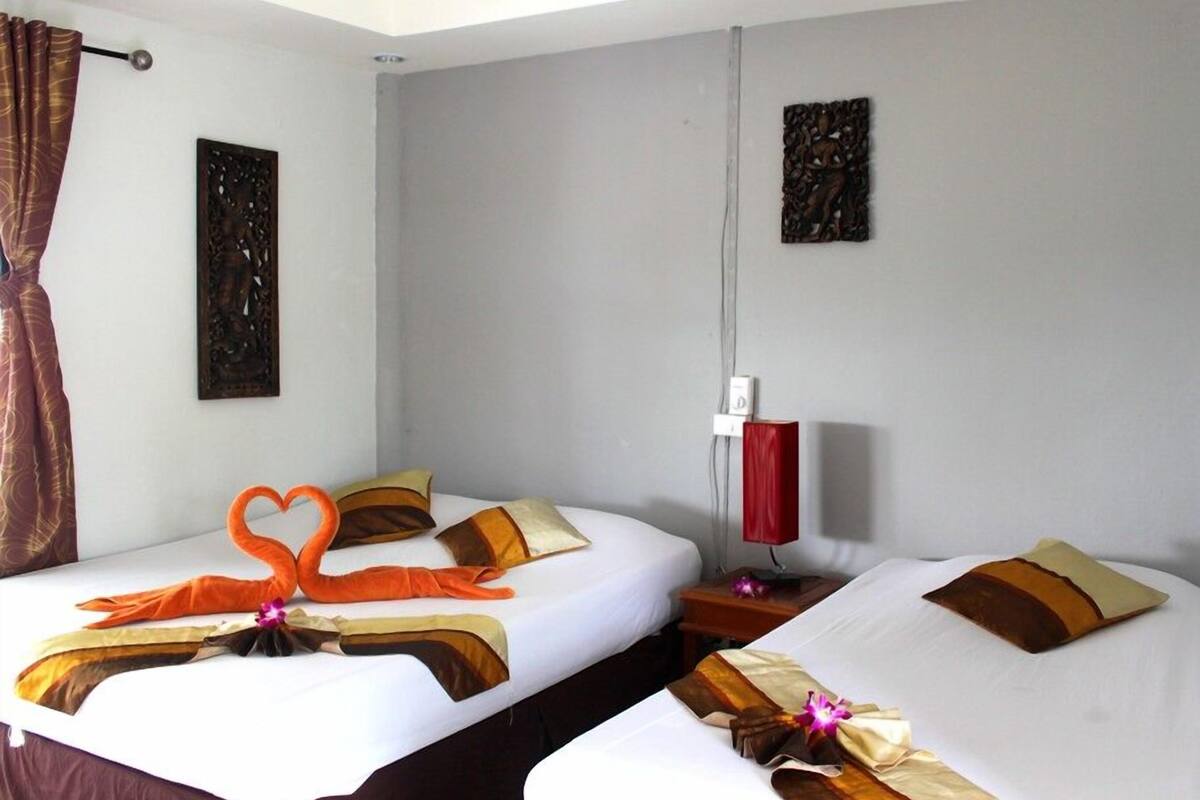 Ein Hotelzimmer mit zwei Betten, jedes mit einer herzförmigen Handtuchgestaltung und passenden Kissen.