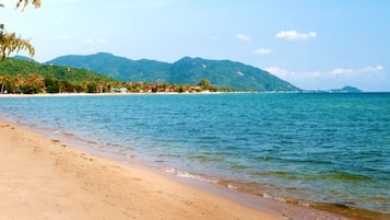 Na praia, espreguiçadeiras, guarda-sóis