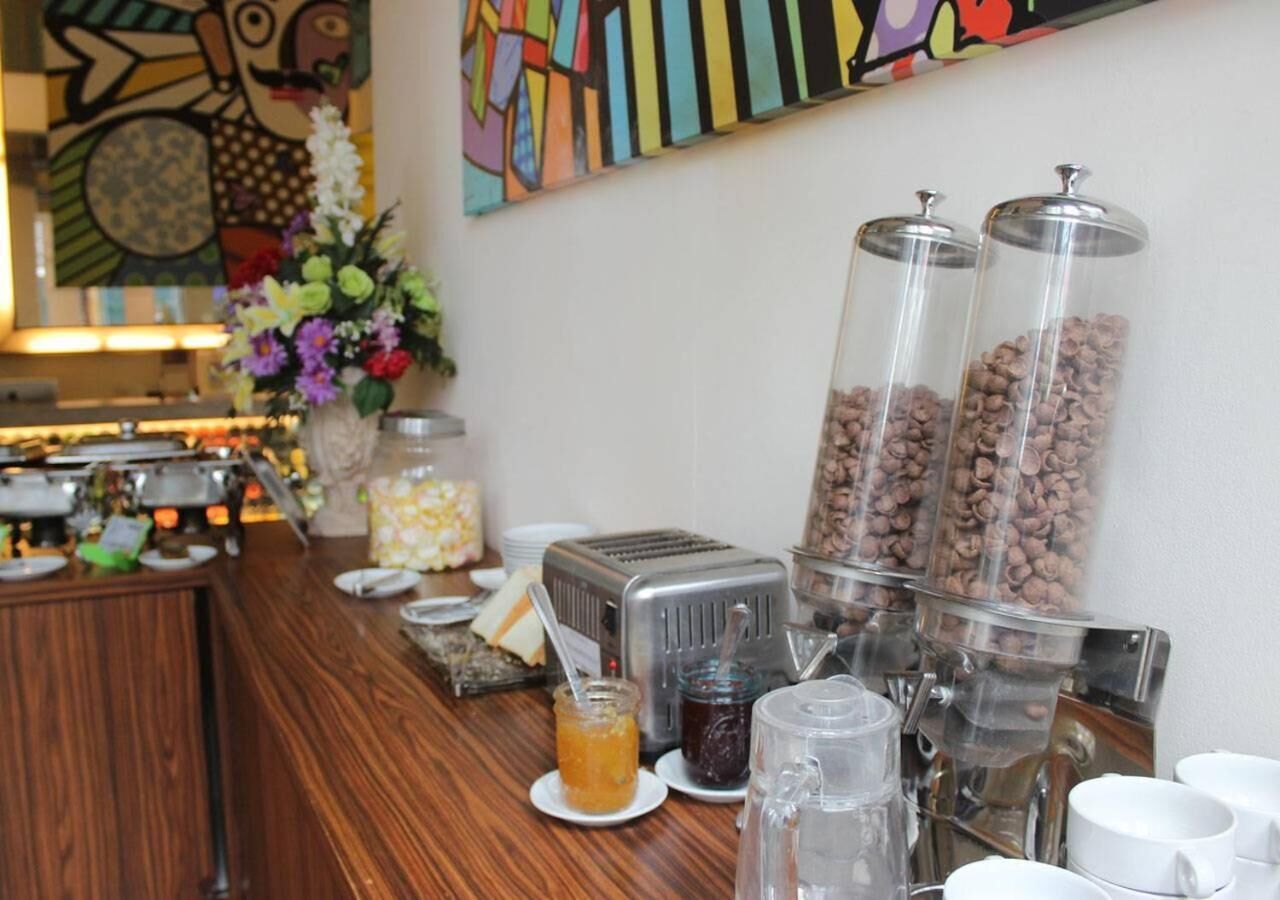 A buffet setup with a toaster, coffee machine, and various food containers.