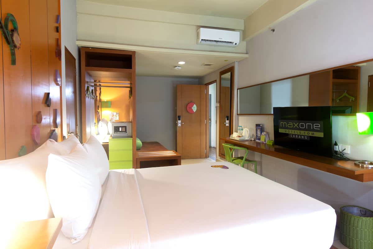 A hotel room with a bed, a desk, a television, and a wardrobe.
