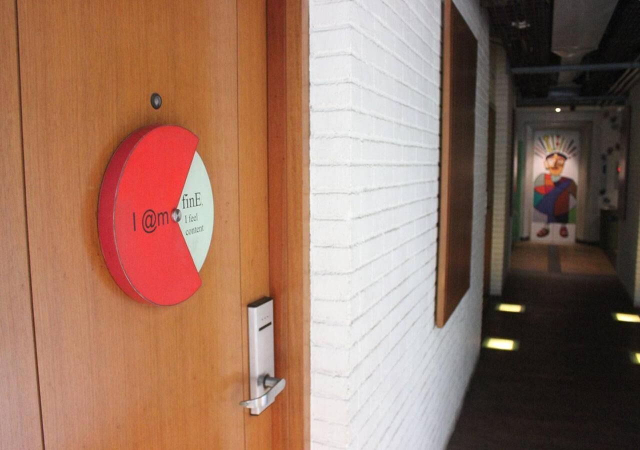 A hotel entrance with a wooden door, a red and white sign, and a corridor with a mural.