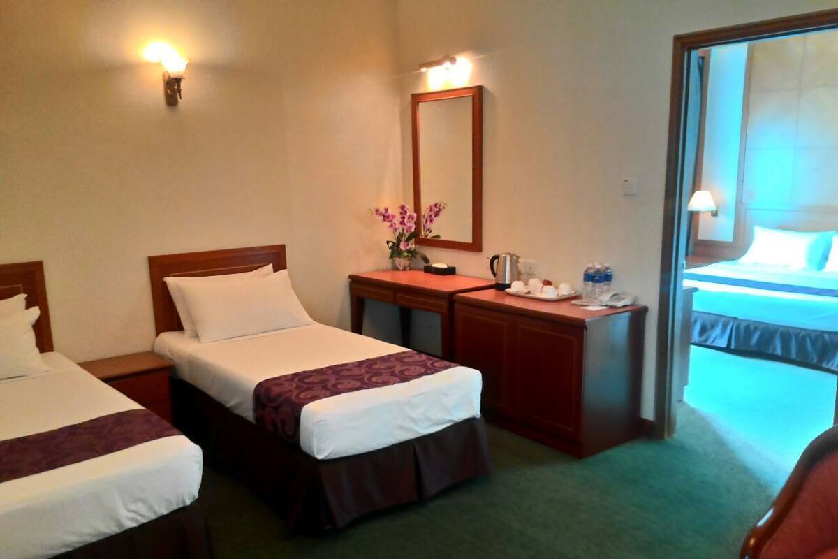 Quarto de hotel com duas camas, uma escrivaninha, um espelho e vista para a varanda.
