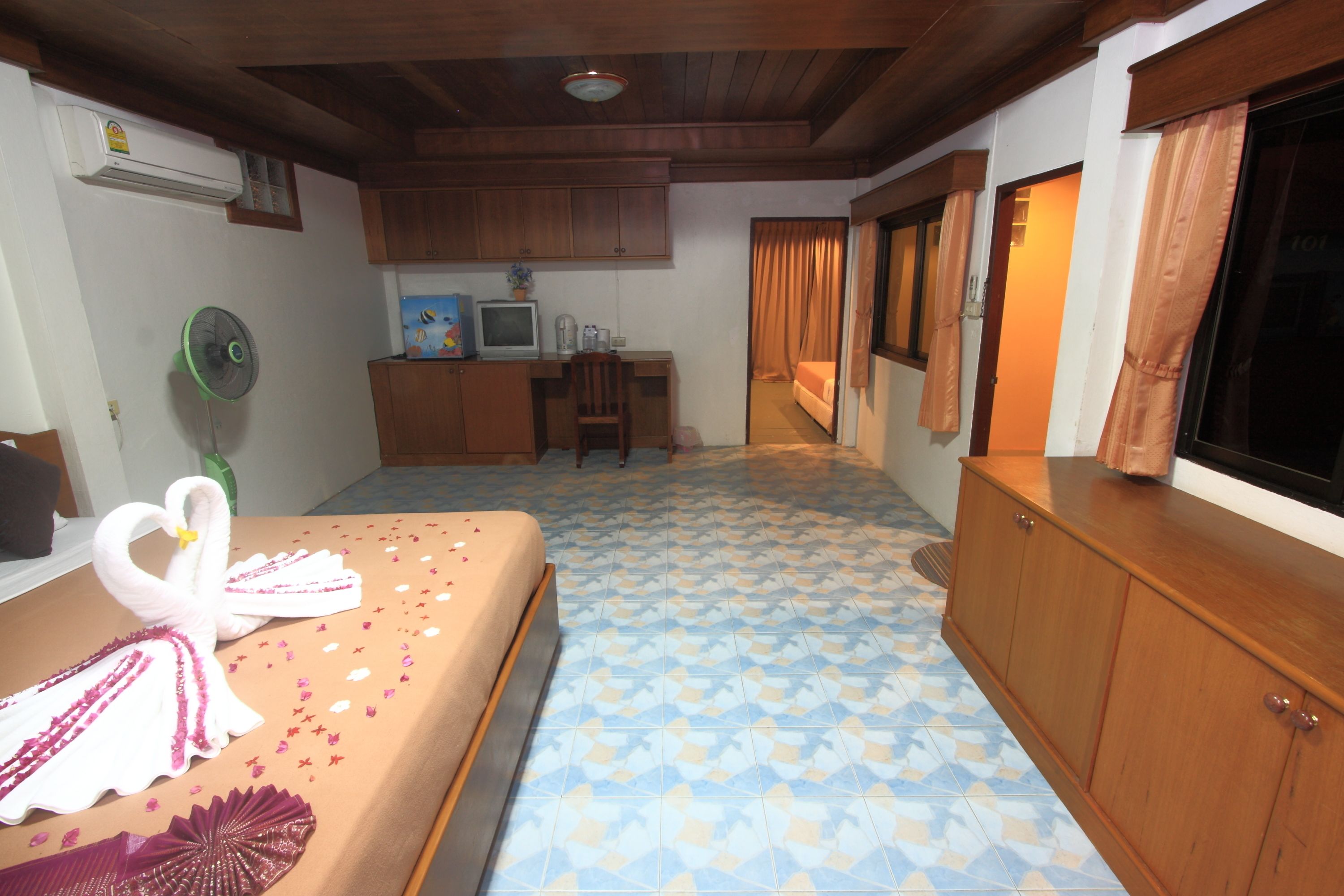 A hotel room with a bed, a desk, a television, and a kitchenette area.
