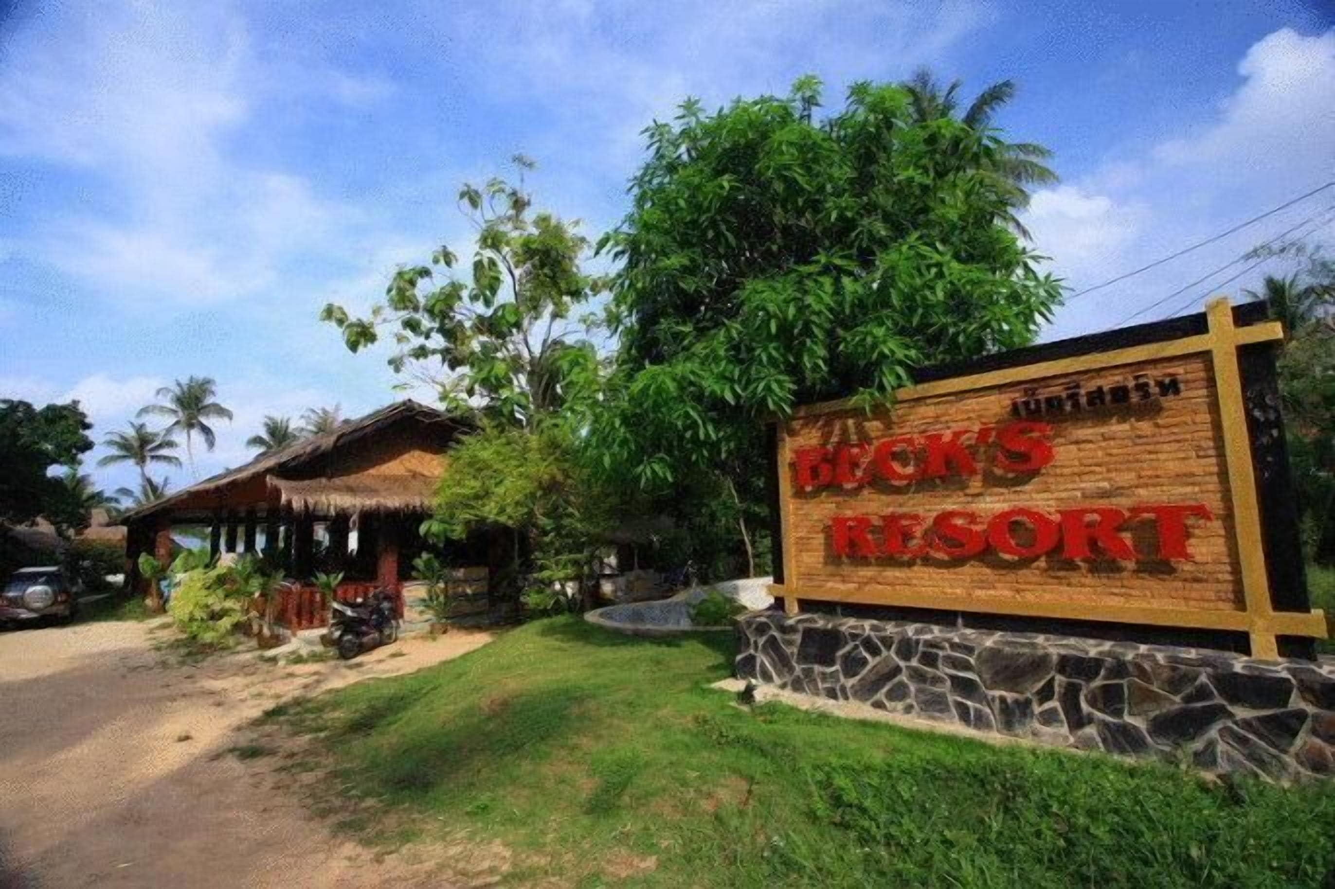 A sign for "Beach's Resort" with a rustic building and lush greenery in the background.
