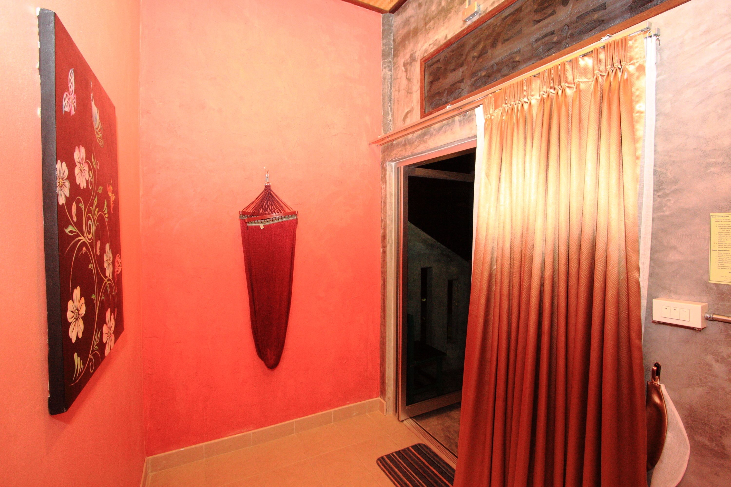 A hallway with a red wall, a door with a curtain, and a hanging red towel.