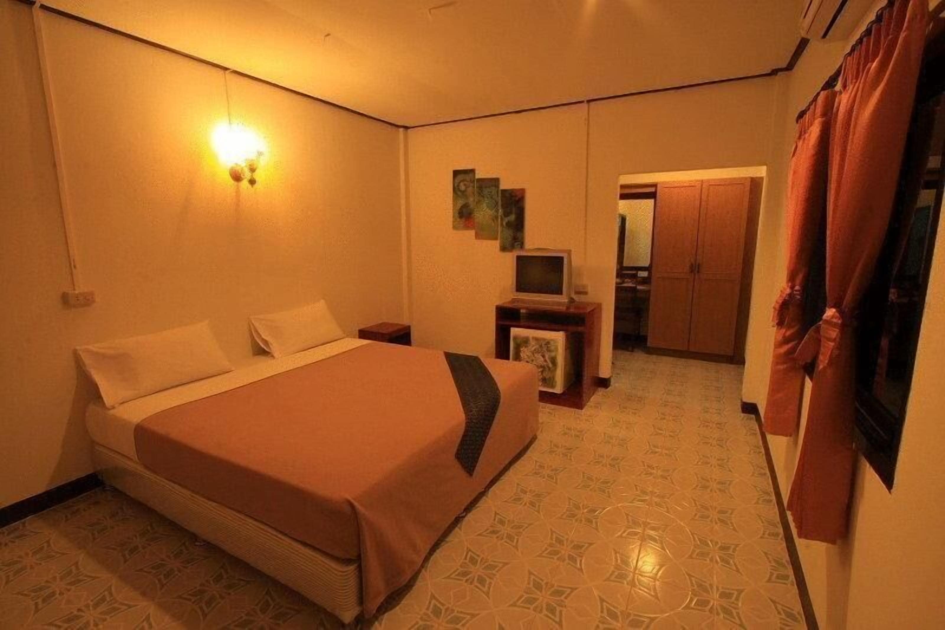 Habitación de hotel con cama, escritorio con computadora, espejo y armario.