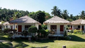 Two thatched-roof cottages with white walls and red doors, surrounded by lush greenery and palm trees. - Beck 's Resort (Ko Pha-ngan)
