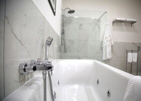 Un bagno moderno con una vasca da bagno ampia, una doccia e un portasciugamani.