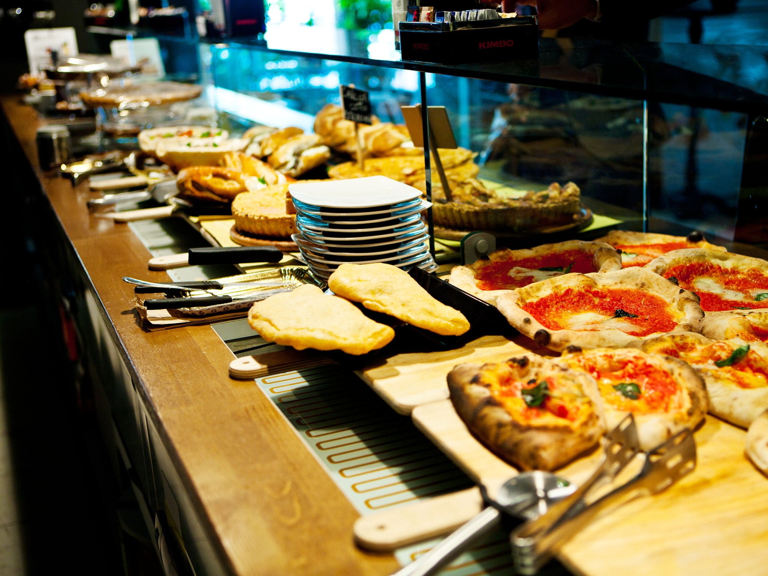 A buffet with various food items including pizzas, pastries, and other baked goods.