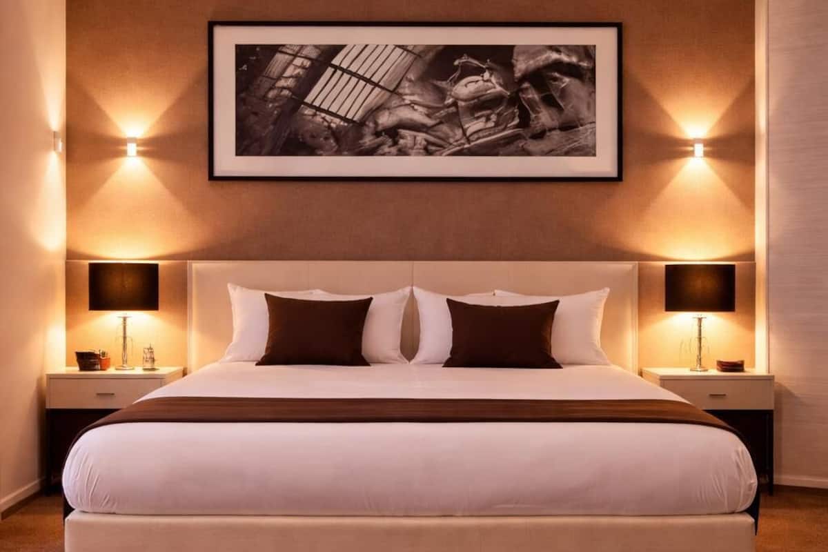 A large bed with a headboard, two bedside tables, and a framed picture above.