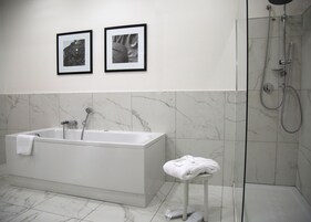 Un bagno moderno con una vasca, una doccia e due quadri appesi al muro.