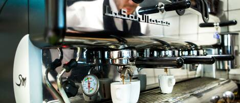Máquina de café com medidor de pressão e duas chávenas brancas.