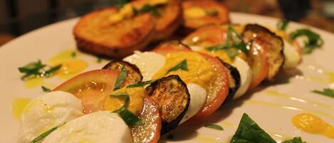 Un plato de comida con rodajas de tomate, mozzarella y albahaca.