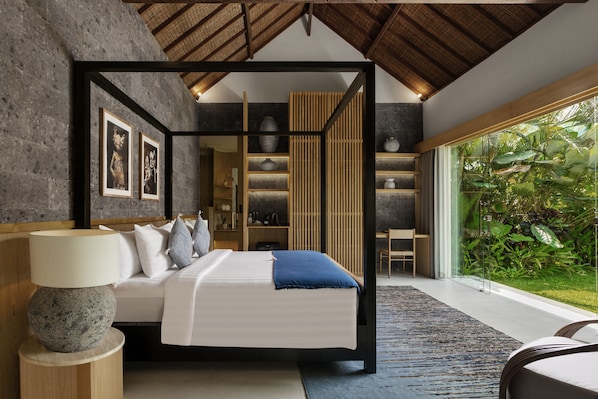 A modern bedroom with a four-poster bed, a large window with a view of greenery, and a built-in shelving unit. - Suara Air Resort Ubud (Ubud)