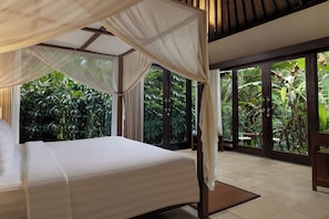 A bedroom with a canopy bed, large windows, and a view of tropical foliage. - Suara Air Resort Ubud (Ubud)