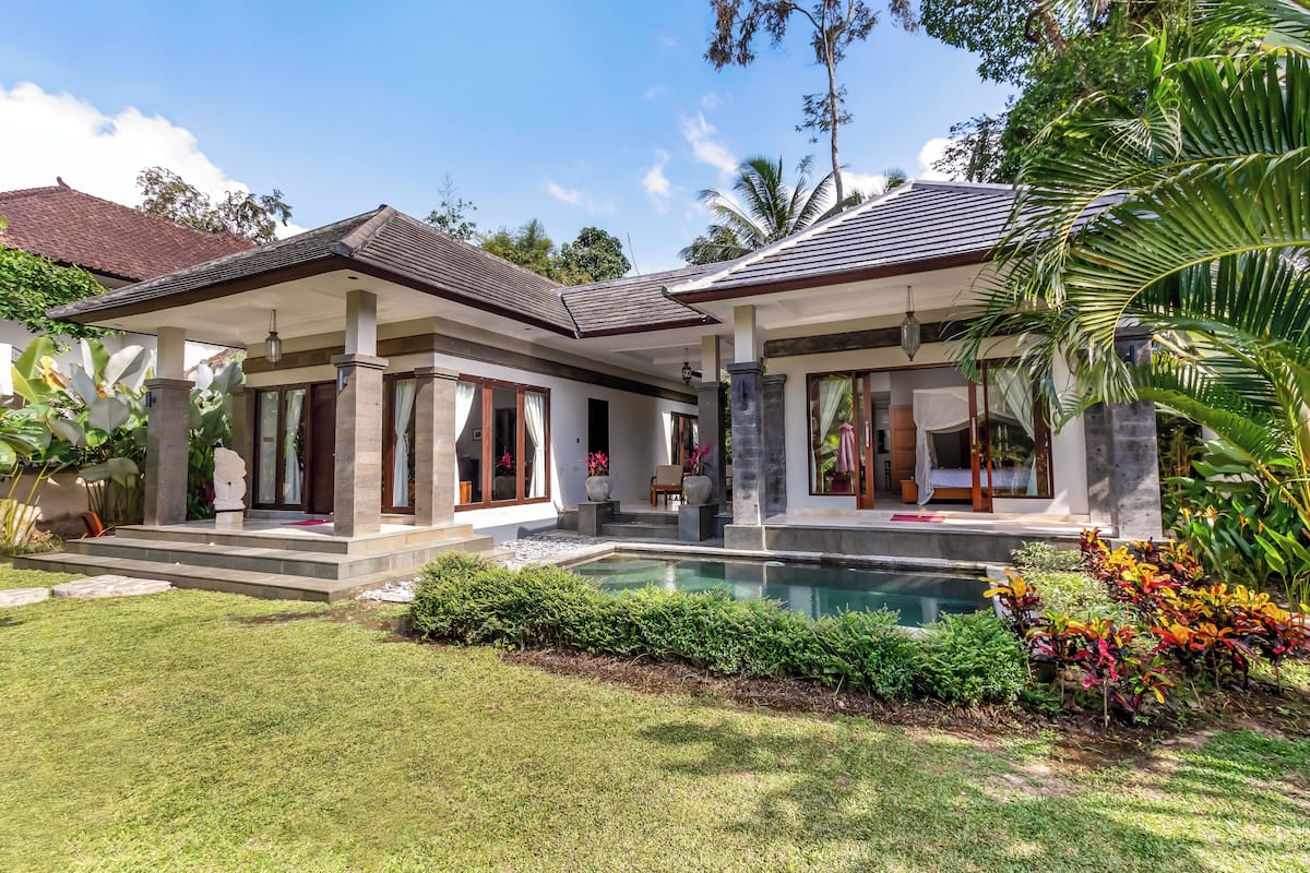Ein modernes Haus mit Swimmingpool, überdachter Terrasse und üppigem Garten.