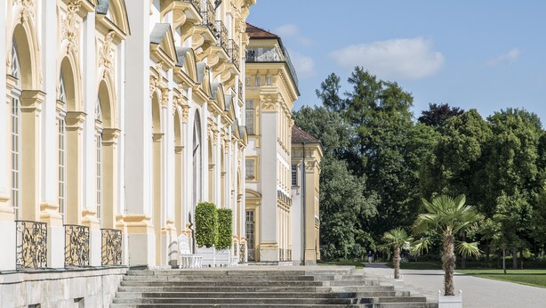 Un imposant bâtiment à l’architecture classique, caractérisé par une façade symétrique, de grandes fenêtres et une entrée centrale surélevée par des marches.