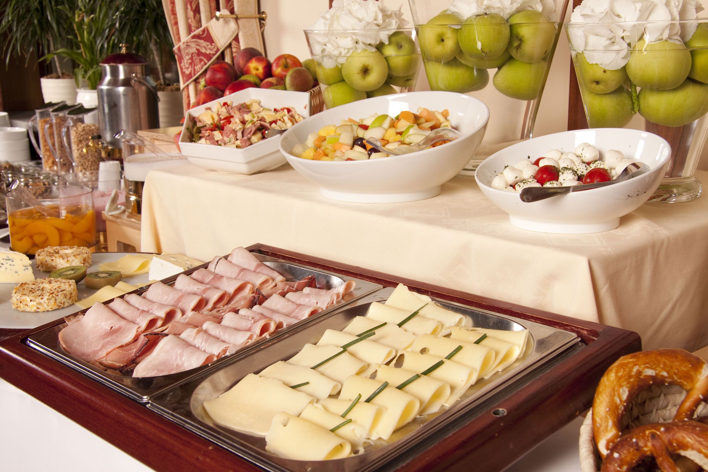 A buffet table with various food items including fruits, cheeses, and meats.