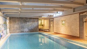 Une piscine intérieure avec des murs en pierre et un espace avec des bancs.
