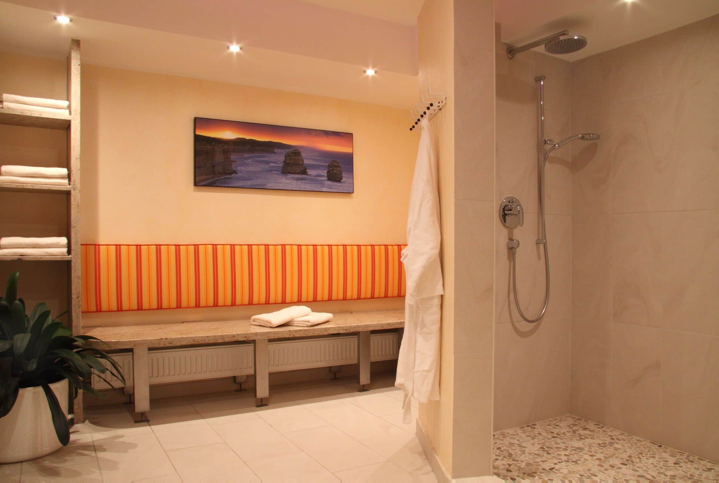 A bathroom with a bench, a shower, and a painting on the wall.