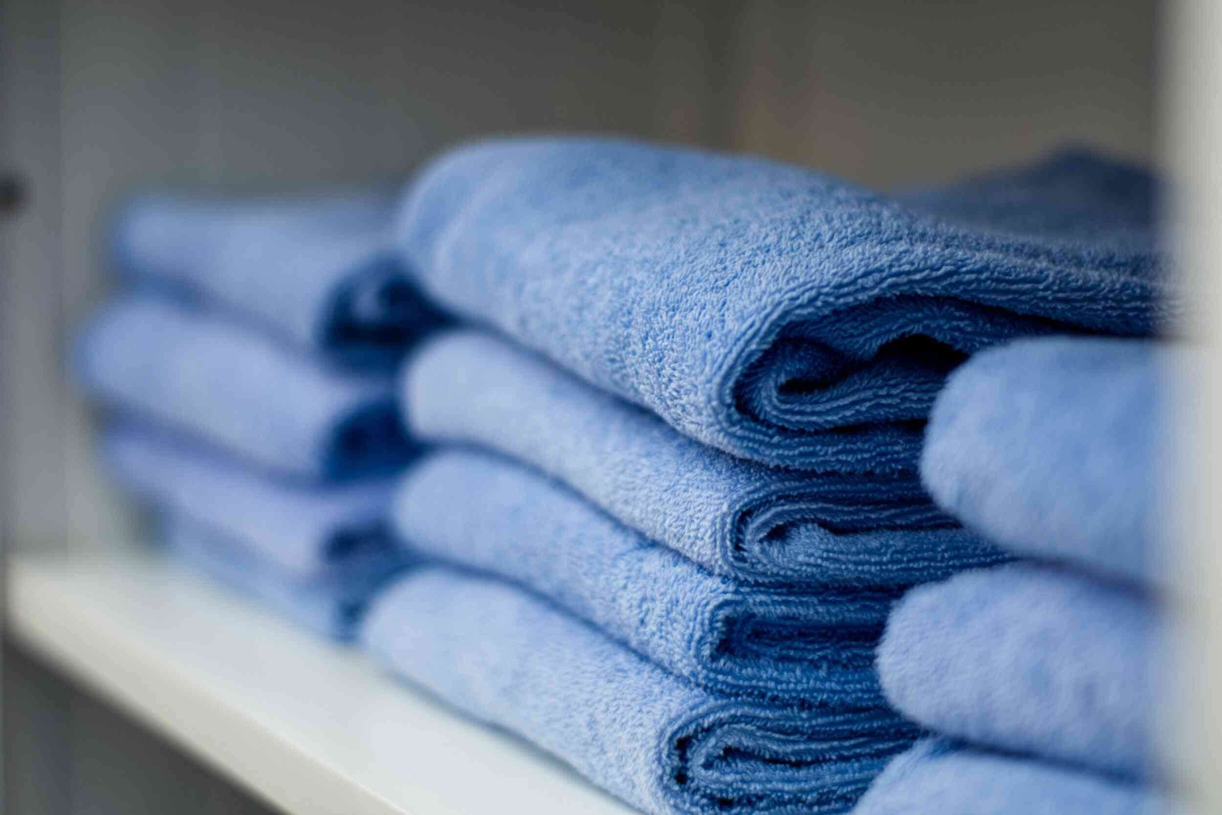 A stack of folded towels on a shelf.