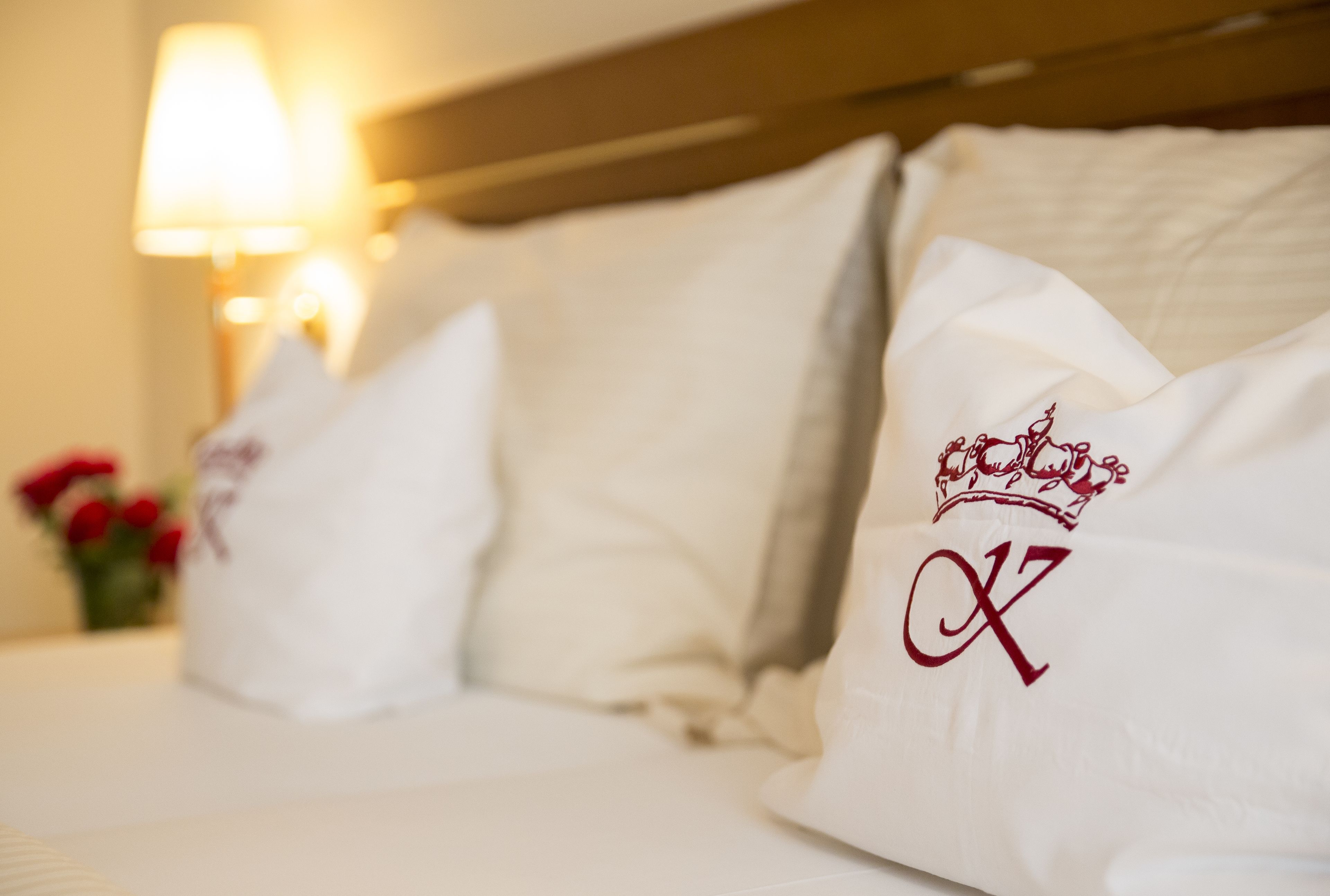 Una cama de hotel con ropa blanca y almohadas, una con un diseño grabado.