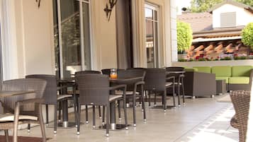 An outdoor patio area with wicker furniture, a table, and a green sofa.
