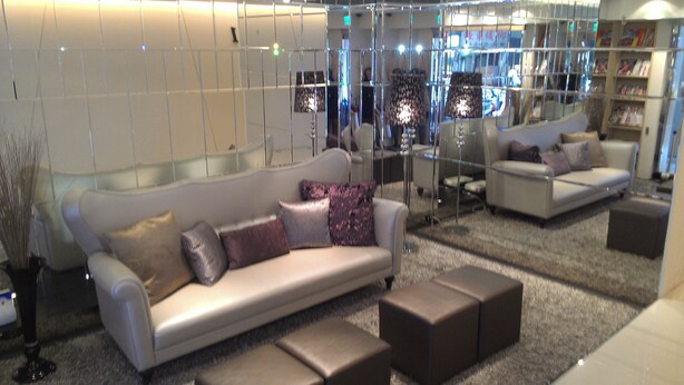 A modern interior with a white sofa, multiple ottomans, and a glass partition. - Royal Hotel (Taipei)