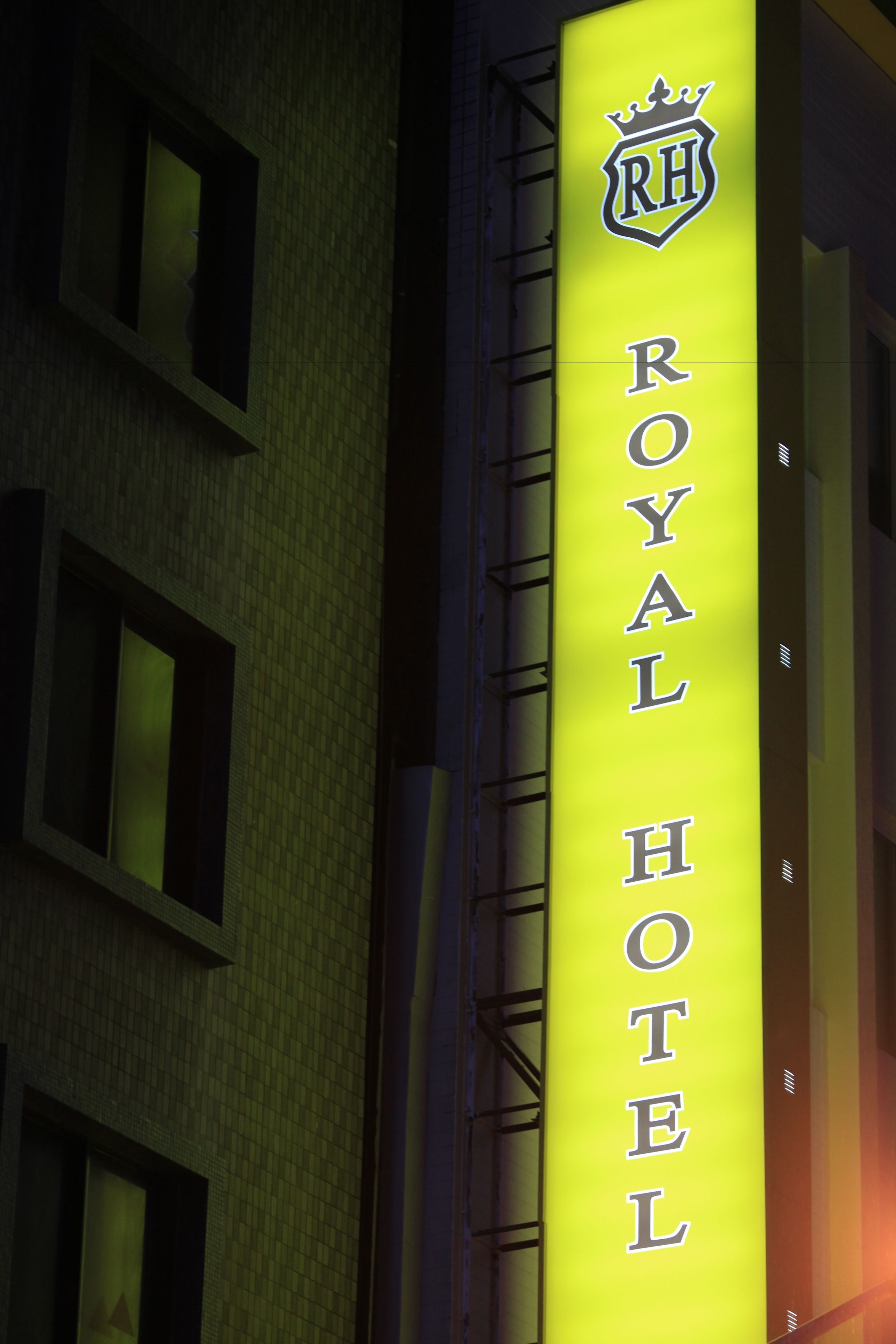 En vertikal neonlys-skiltning for Royal Hotel med et kronelogo.
