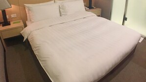 A neatly made bed with white linens in a hotel room. - Royal Hotel (Taipei)