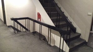 A staircase with black railings and a red fire extinguisher on the wall. - Royal Hotel (Taipei)