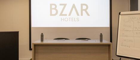 A reception desk with a screen displaying 'BZR HOTELS' and a whiteboard listing hotel locations.