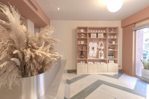 A reception area with a potted plant, a wooden display unit with various items, and a window with a view. - Smart Hotel (Rome)