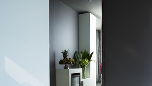 Une salle de bain moderne avec une grande baignoire, un petit lavabo et un miroir au-dessus. On y trouve une plante sur le comptoir et une fenêtre qui laisse entrer la lumière naturelle.