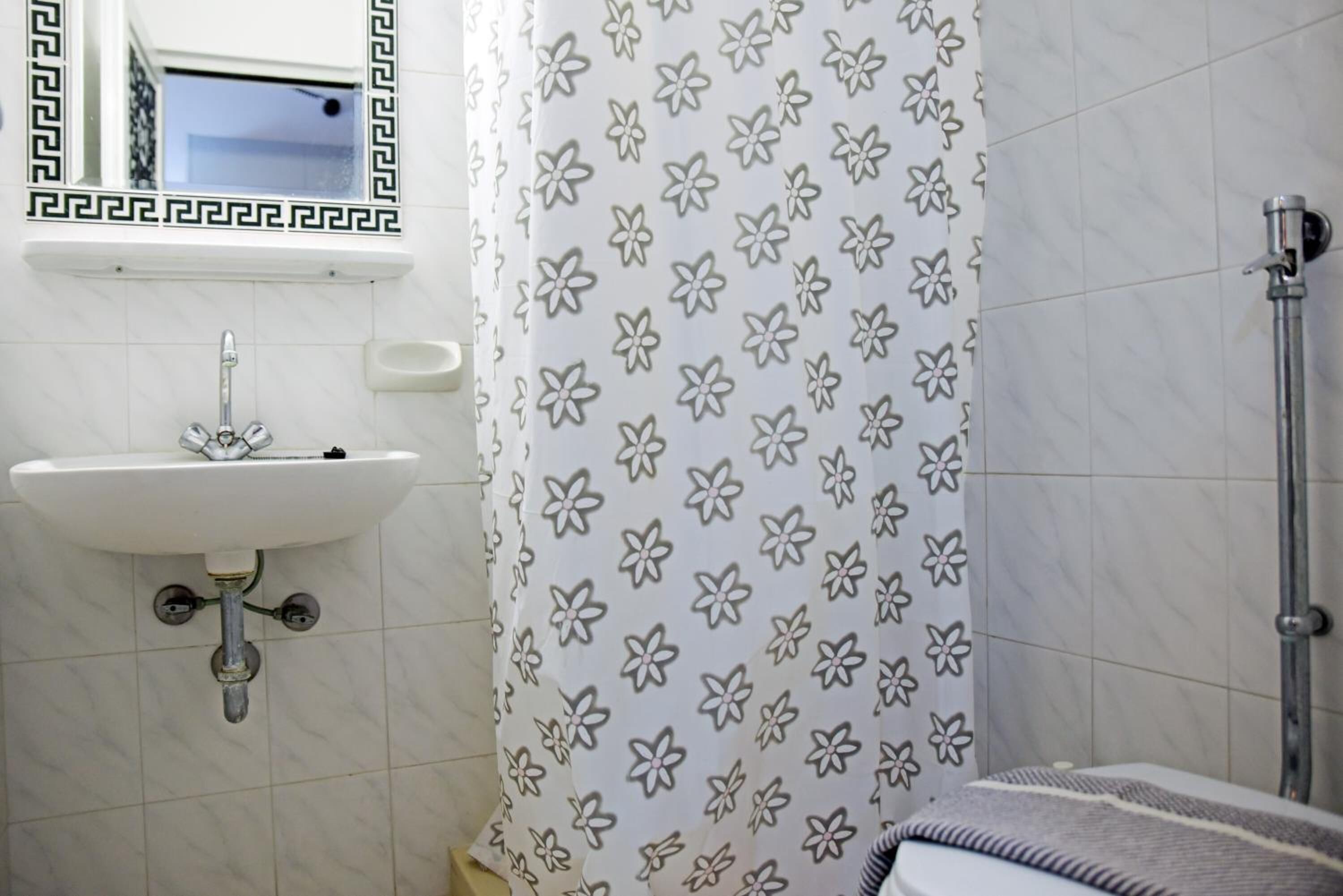 A bathroom with a white sink, a mirror, and a shower.