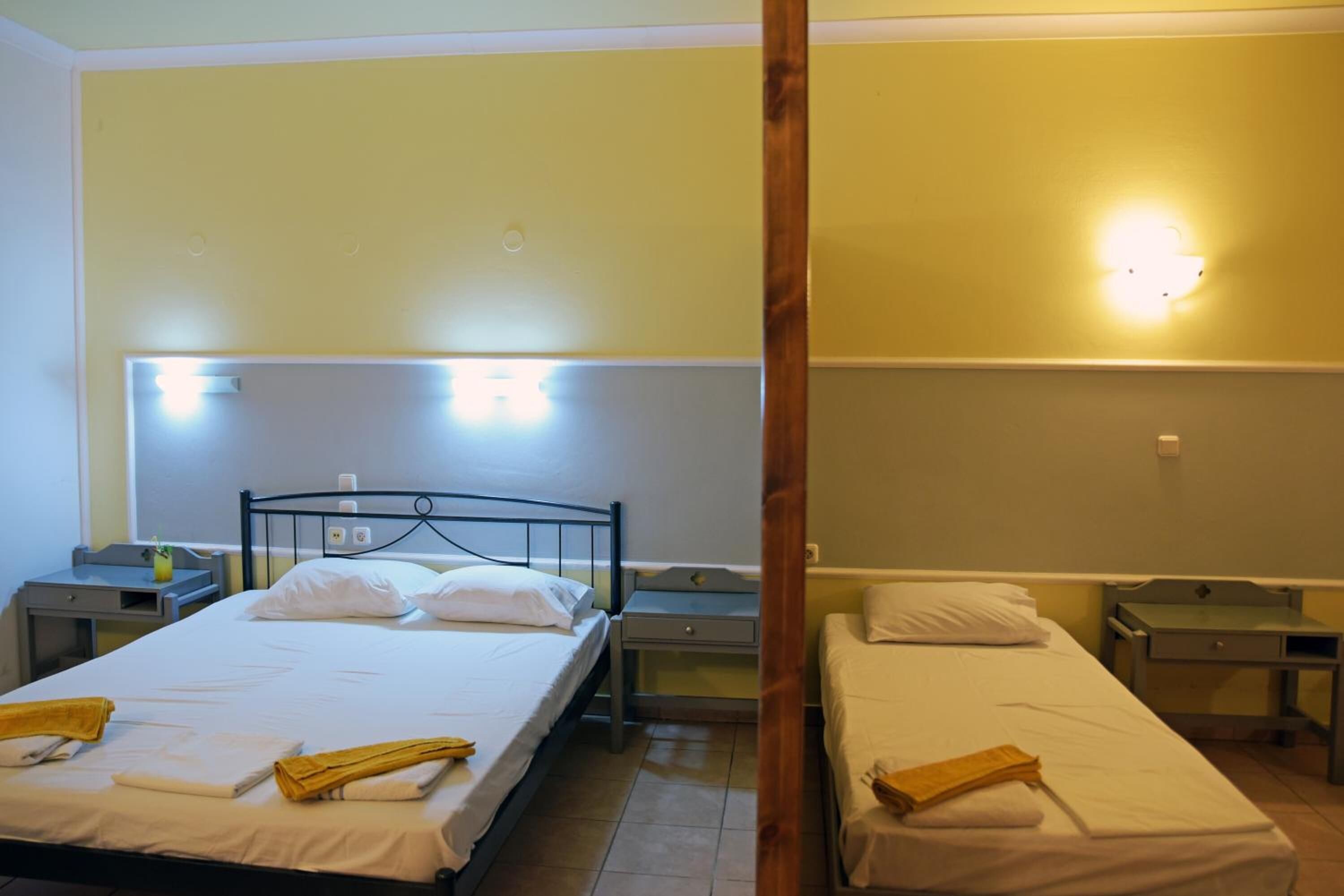 A hotel room with two single beds, each with a nightstand and a lamp.