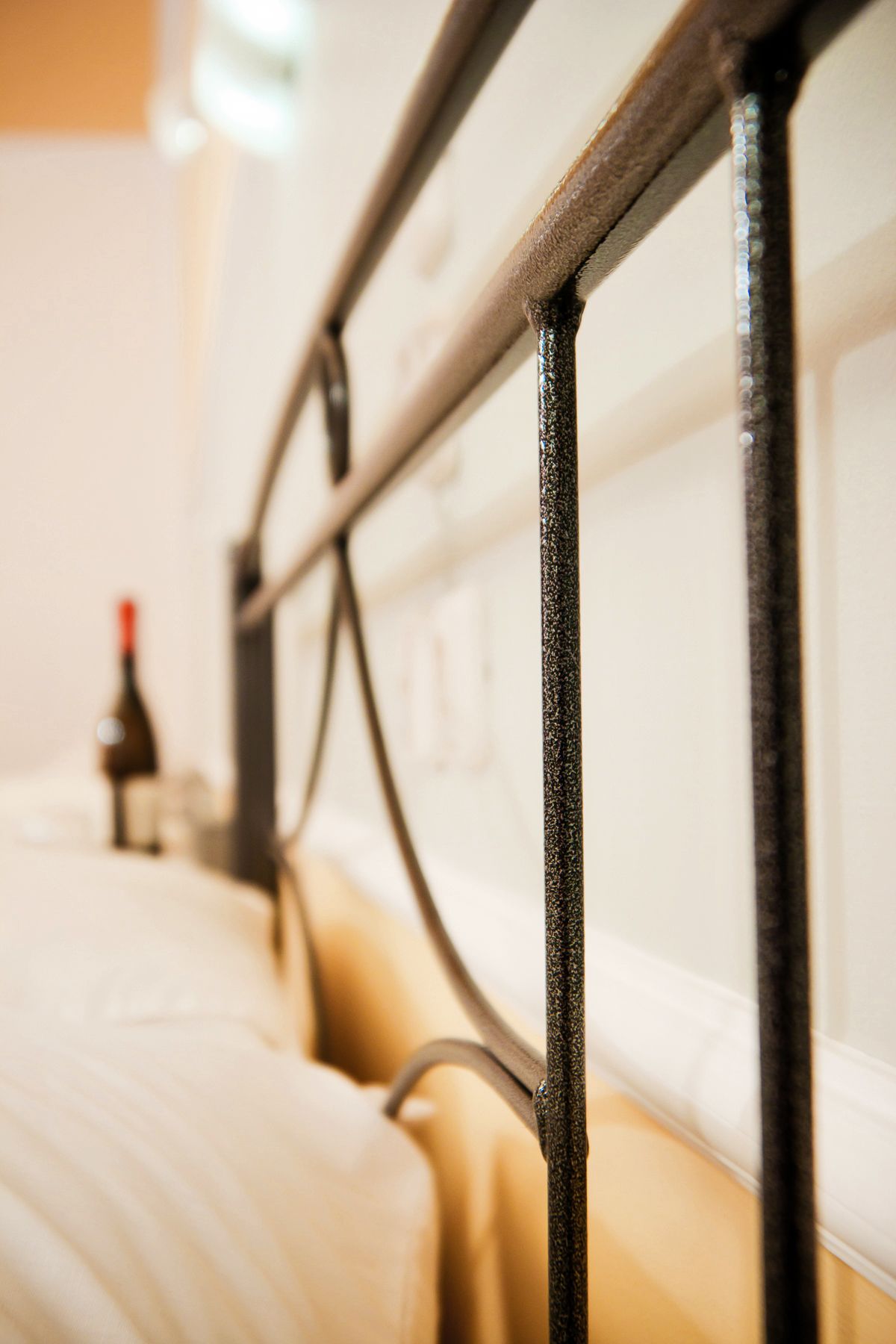 Um close-up de uma estrutura de cama de metal com um colchão e uma garrafa ao fundo.