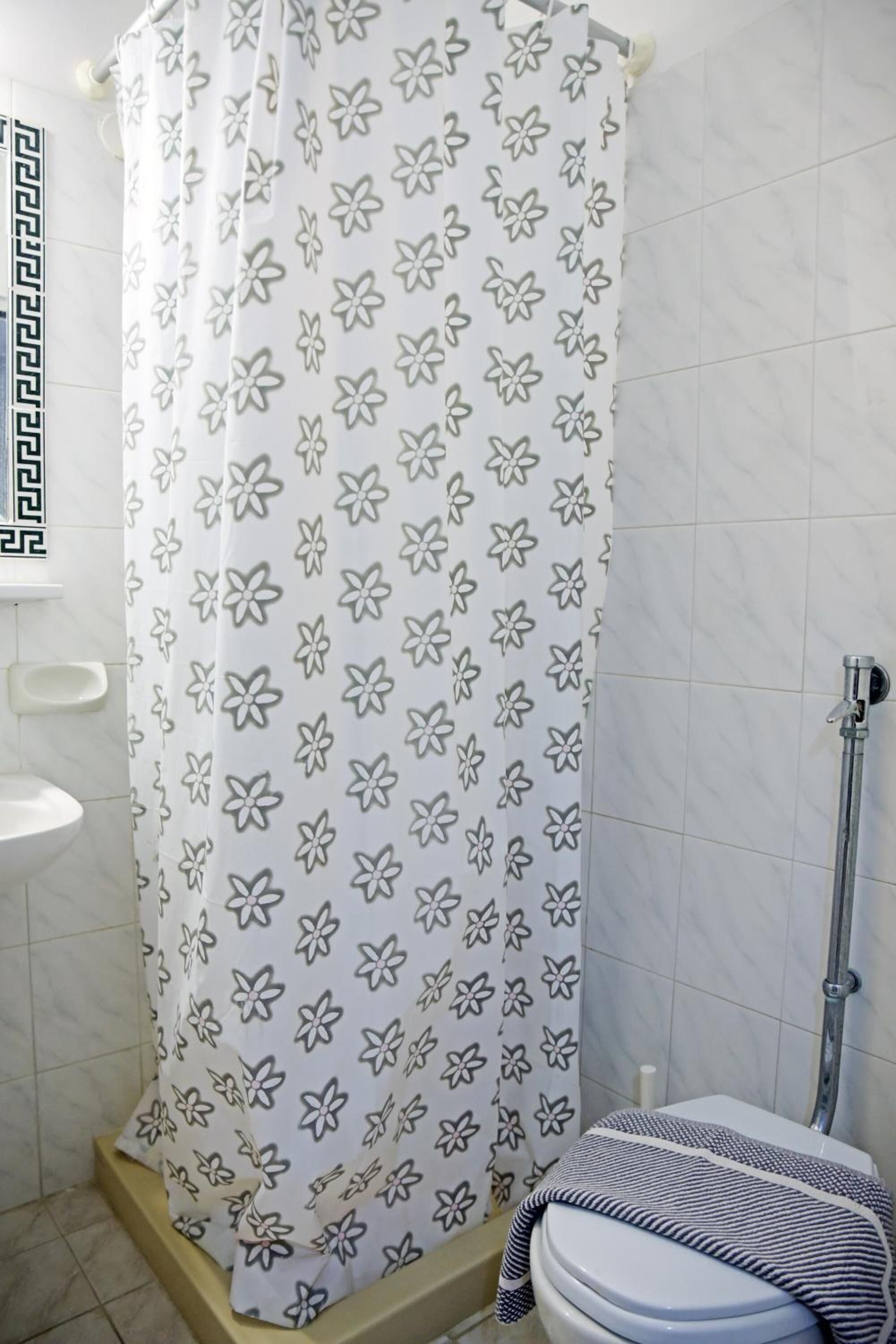 Ein Badezimmer mit Duschvorhang mit Blumenmuster, Toilette und Bidet.