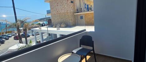 A balcony with a table and chairs, a view of a building under construction, and a clear sky.