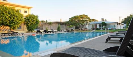 A swimming pool with lounge chairs and a building in the background.