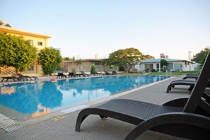 A swimming pool with lounge chairs and a building in the background. - Falirala Central (Rhodes)