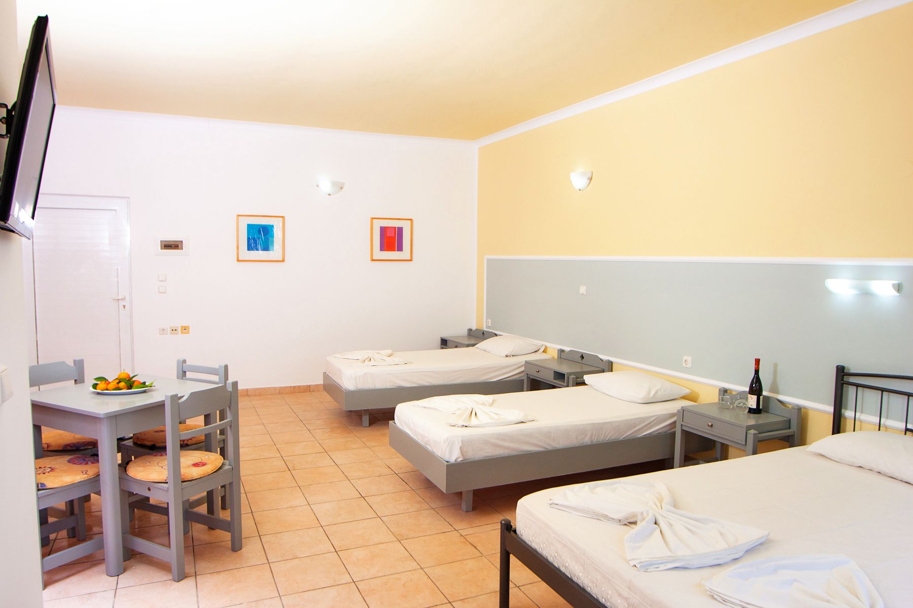 Una camera d'albergo con due letti, una scrivania con una sedia e un tavolo da pranzo.
