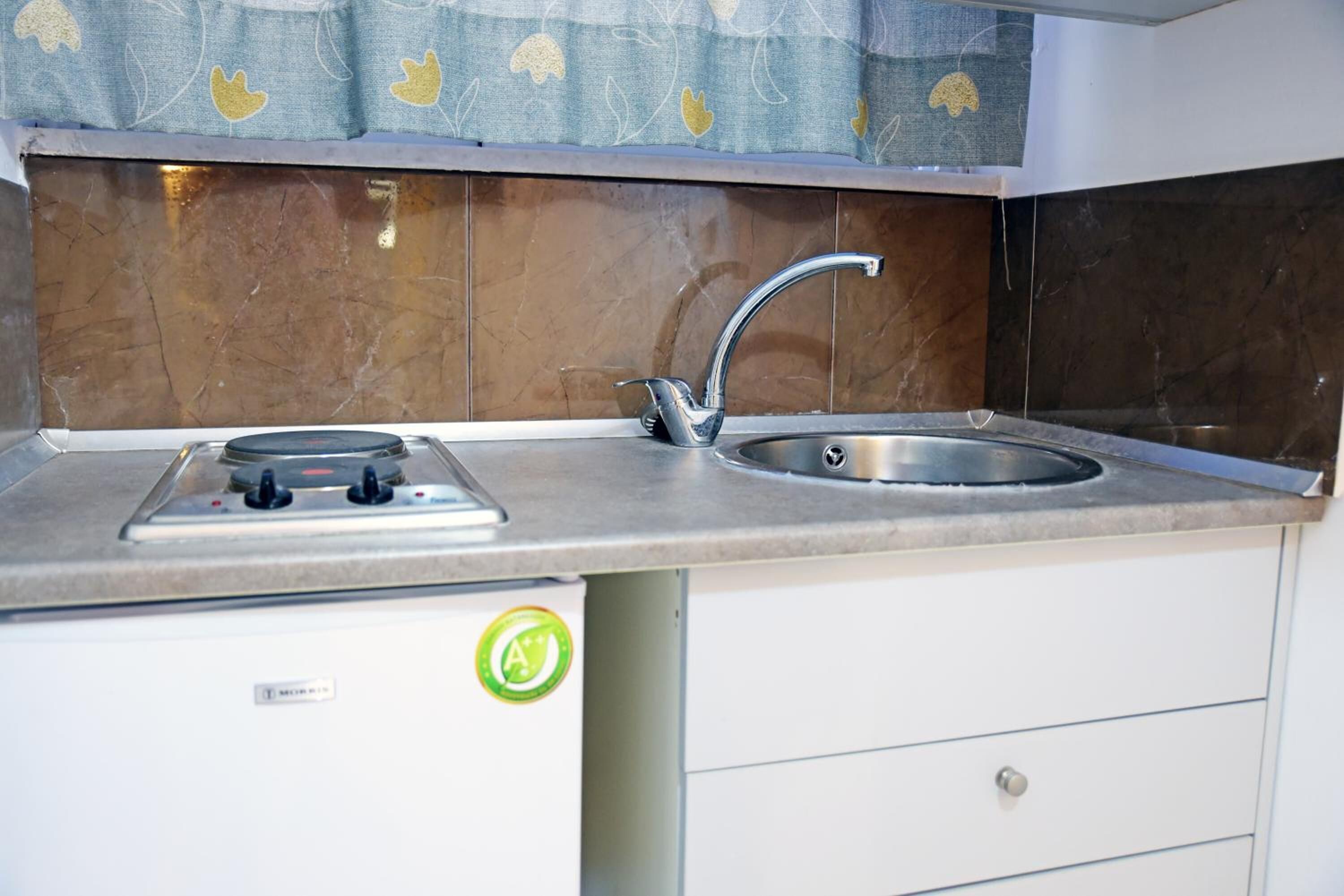 A kitchen with a stainless steel sink, a gas stove, and a white cabinet below.