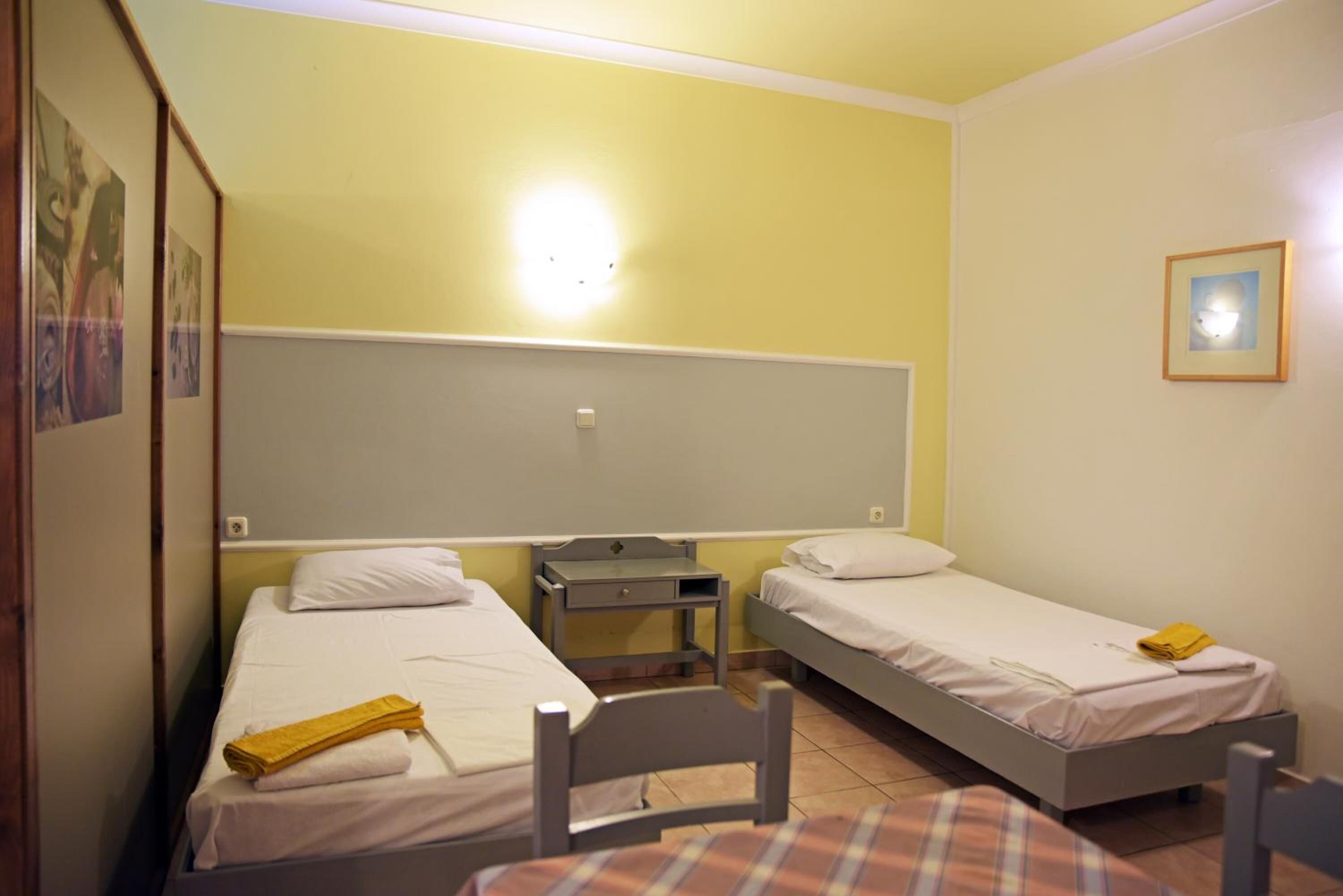 Una habitación con dos camas individuales, un escritorio pequeño y una silla.