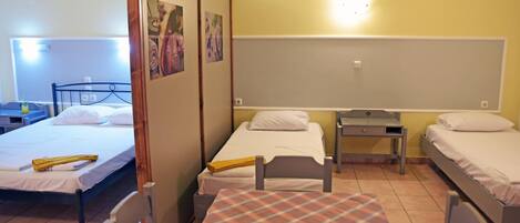 A dormitory room with two single beds, a small table, and a chair.