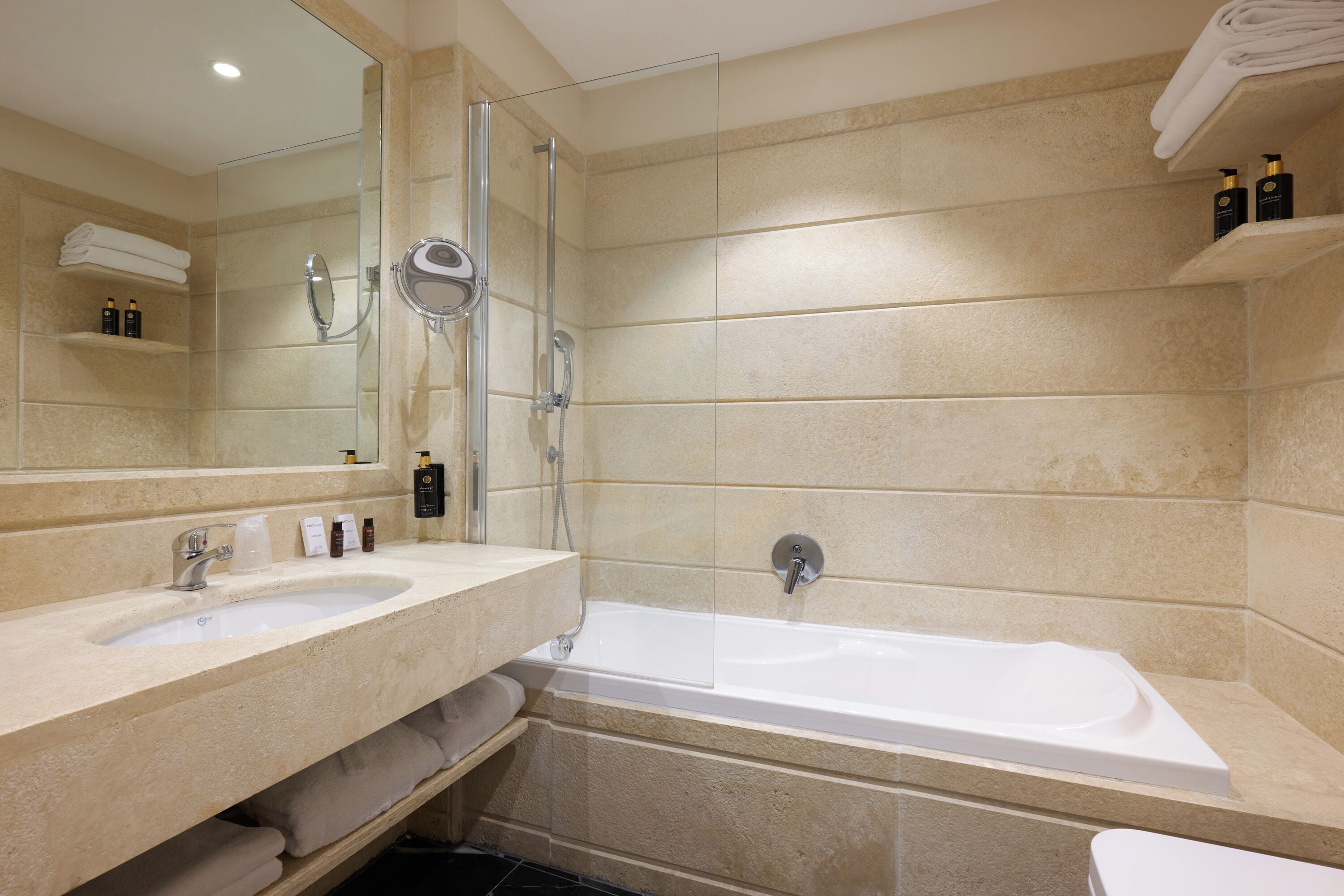 Un baño con lavamanos doble, bañera, ducha con mampara de vidrio y espejo.